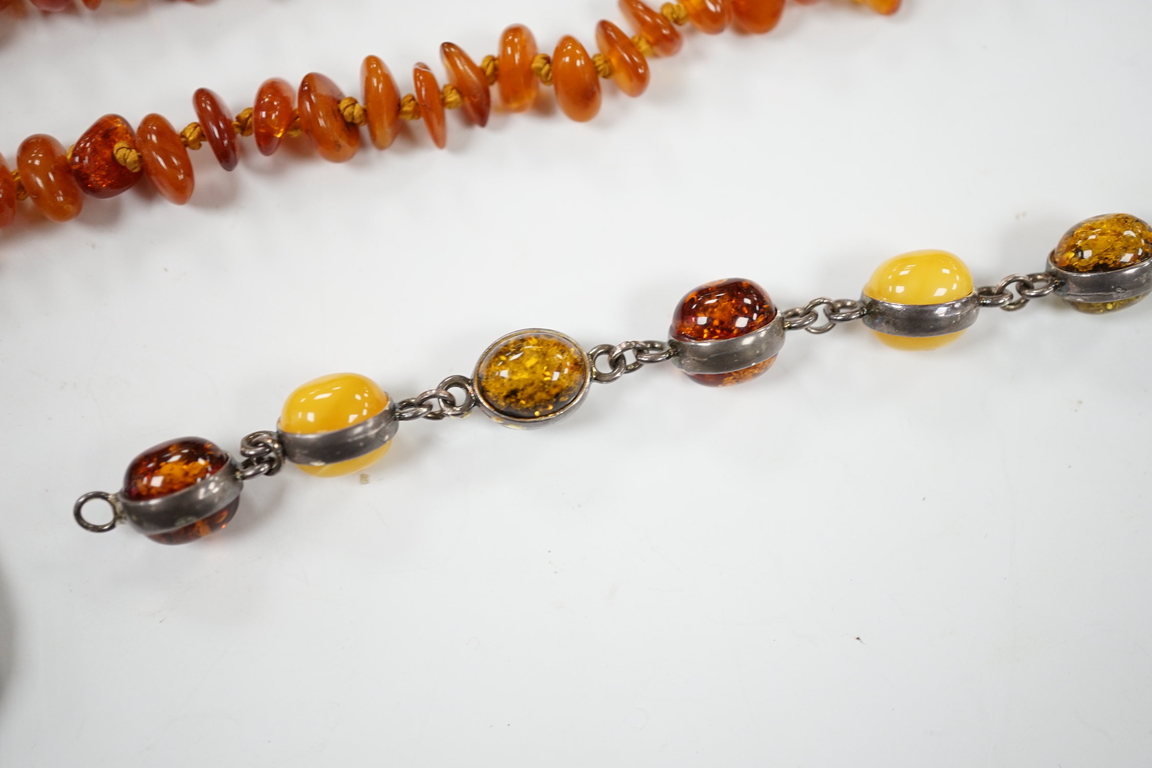 Two white metal and Baltic amber pebble set bracelets, one stamped 925, largest 25cm, a pair of similar drop earrings and an amber necklace.